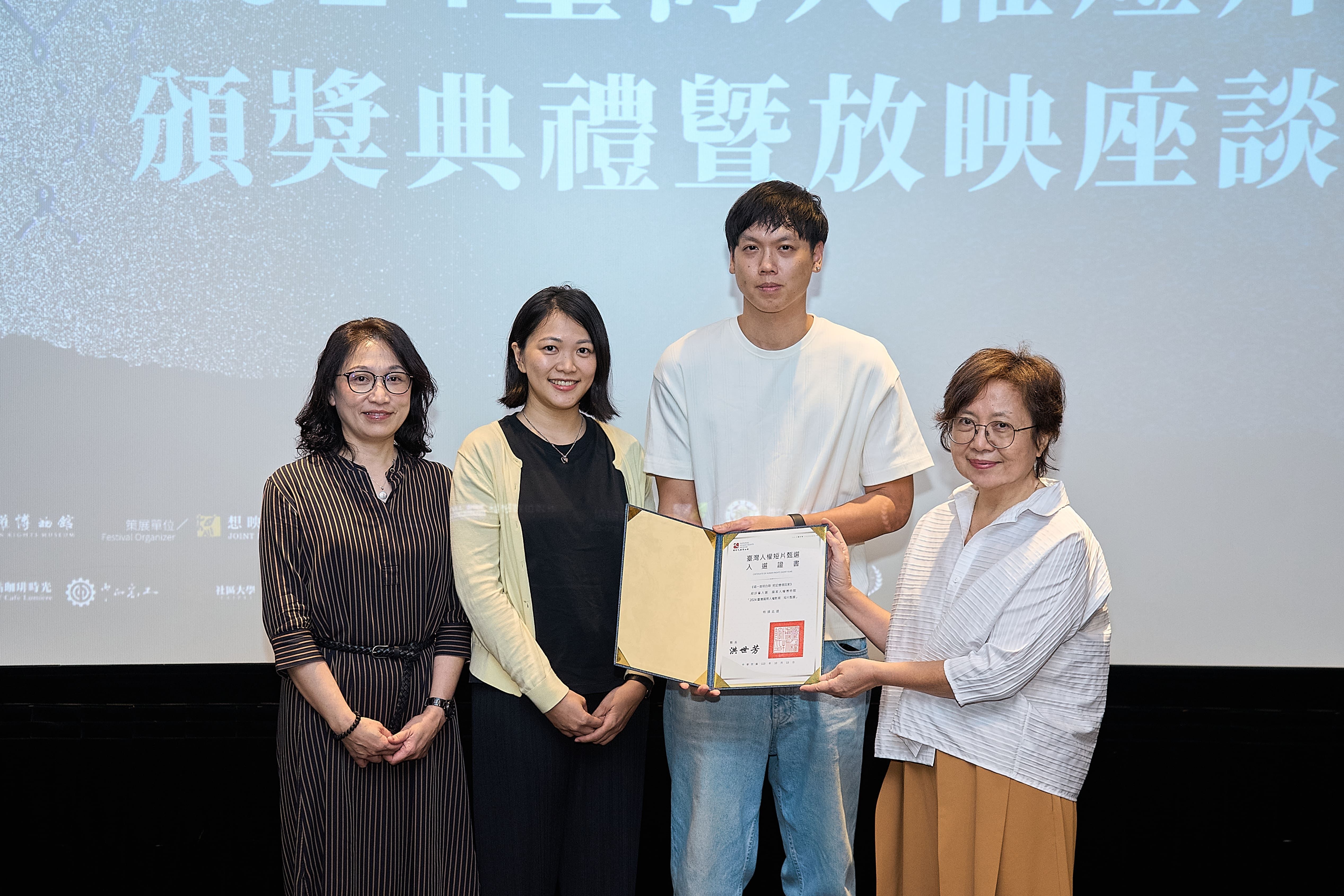 策展人范情(右1)頒贈入選證書予《唱一首明白歌把記憶領回家》導演卓煥鈞(右2)、何思瑩(左2)和製作人宗立婷(左1)。(圖/國家人權博物館)