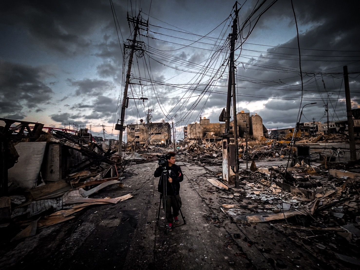 日本能登半島輪島朝市受到強震後大火摧殘 ， 滿目瘡痍， 鏡電視派兩組特派記者前往災區前線，此為攝影記者呂紹博 。
