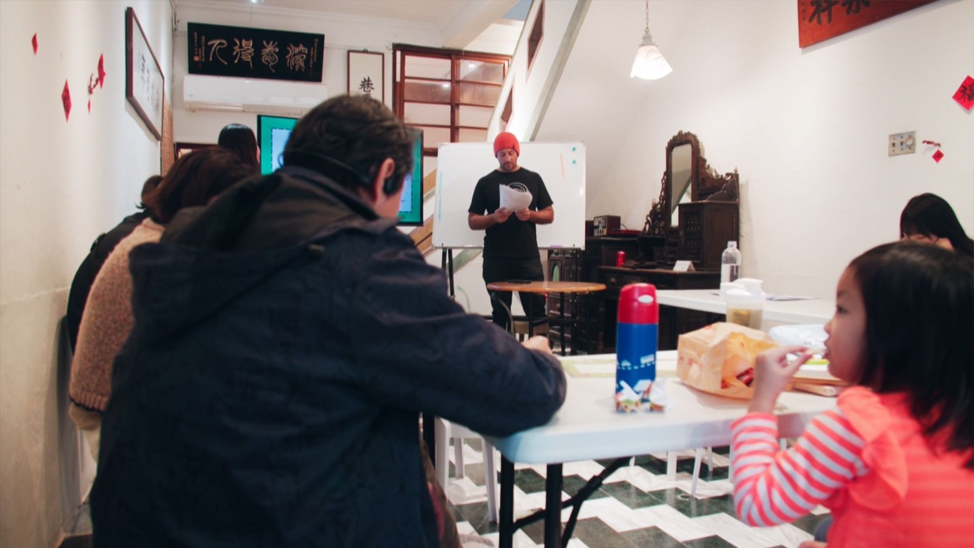 宜蘭頭城國際生活村計畫，這五年吸引上百位國際人士移居。圖為外籍人士教店家實用英文，金魚厝邊團隊今年舉行小評比，頒發自製的「雙語友善旗幟」，讓店家掛在店外吸引更多國際客。