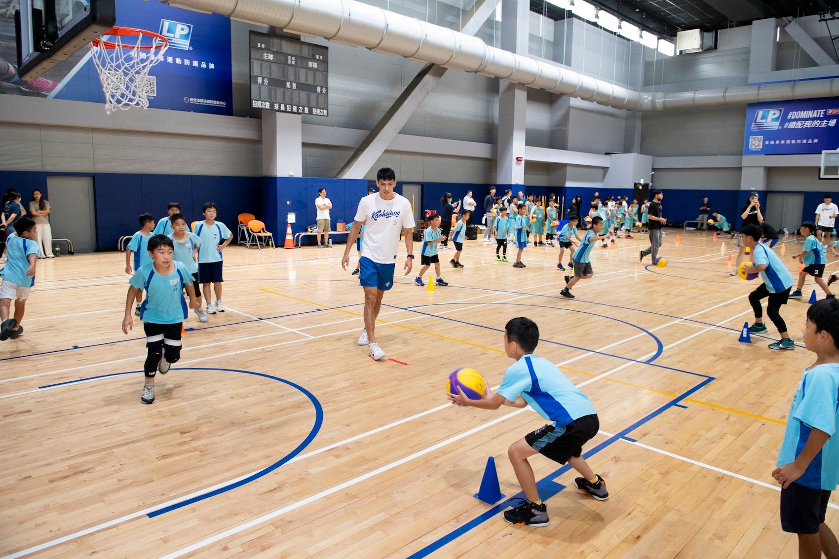 高雄全家海神球員唐維傑，擔任客座教練，指導力行國小籃球隊球員傳球技巧。（遠雄文教公益基金會提供）