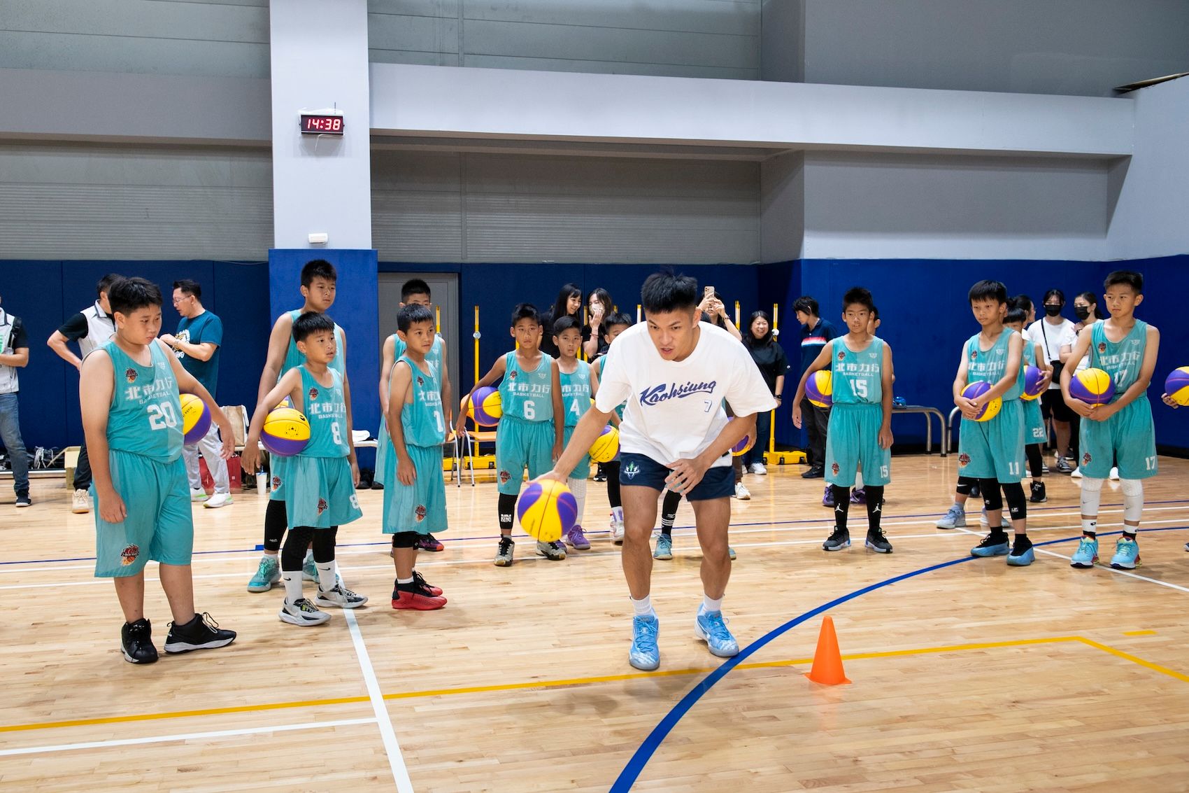 高雄全家海神球員唐維傑，擔任客座教練，指導力行國小籃球隊球員傳球技巧。（遠雄文教公益基金會提供）
