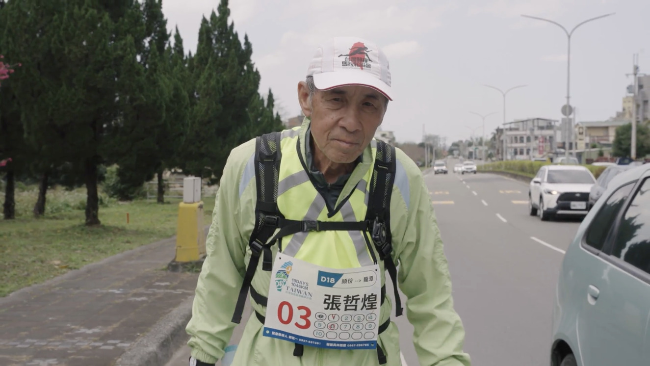 紀錄片《人吶,為什麼要跑步?》中74歲的張哲煌帶著愛妻的遺照參加環台長跑。(牽猴子提供)
