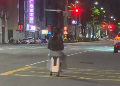 台中市中清路今凌晨出現奇特一幕,1名女子竟騎著電動行李箱上路,並沿著道路一路前進。(threads yoyo_840423授權提供)