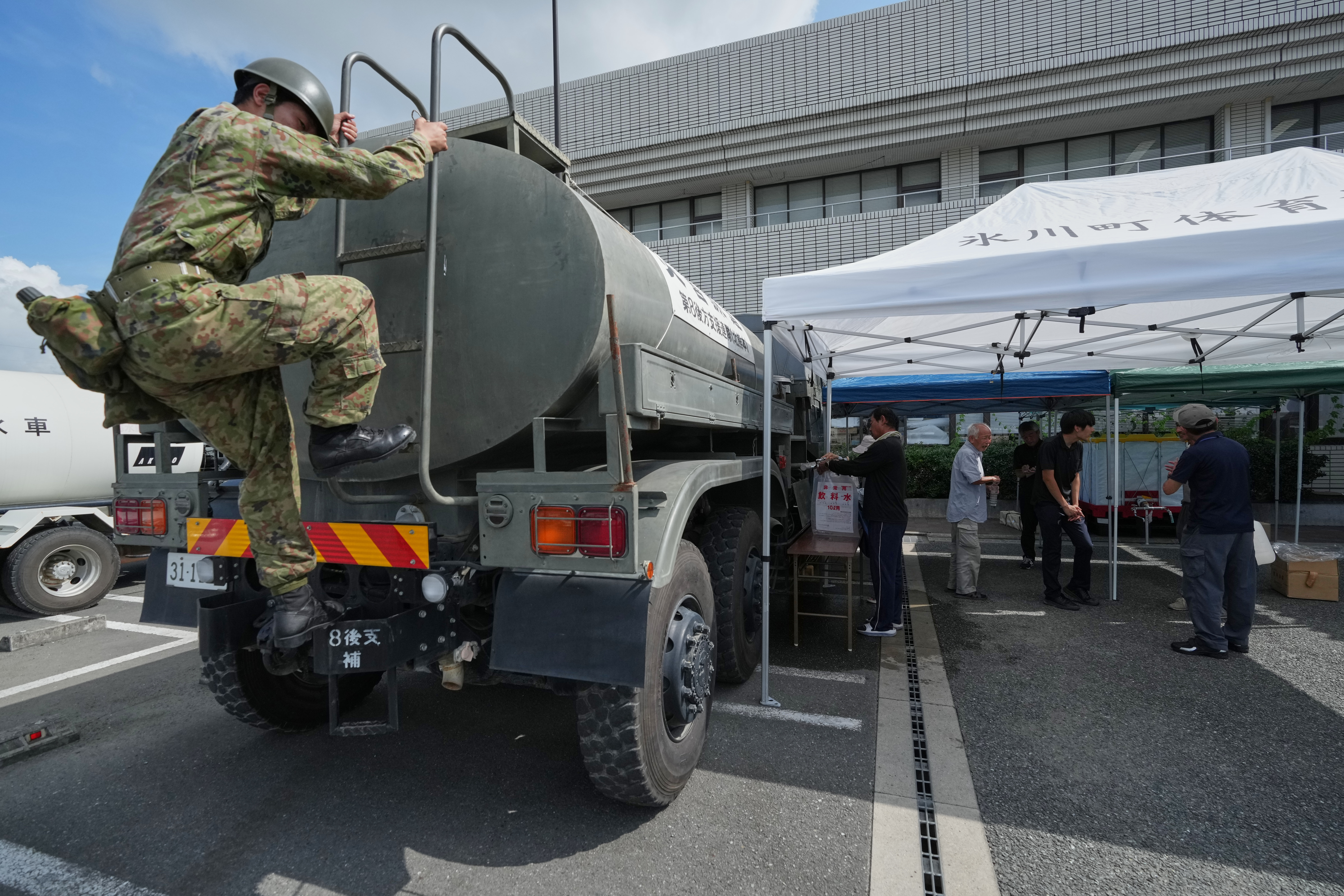 在日本熊本縣冰川市,一名自衛隊員正在檢查一輛向地震災民運送飲用水的供水車。(AP)