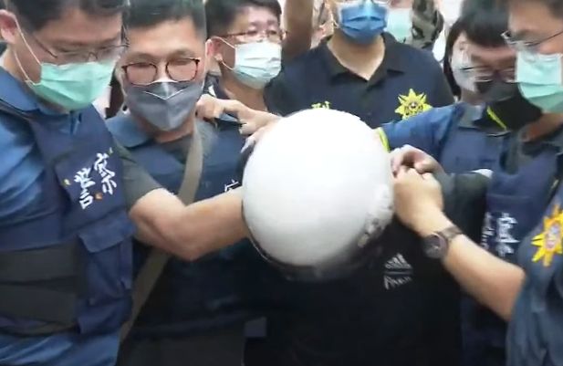 台南殺警案嫌犯林信吾(戴白色安全帽者)落網後,於23日上午被押解進警局。
