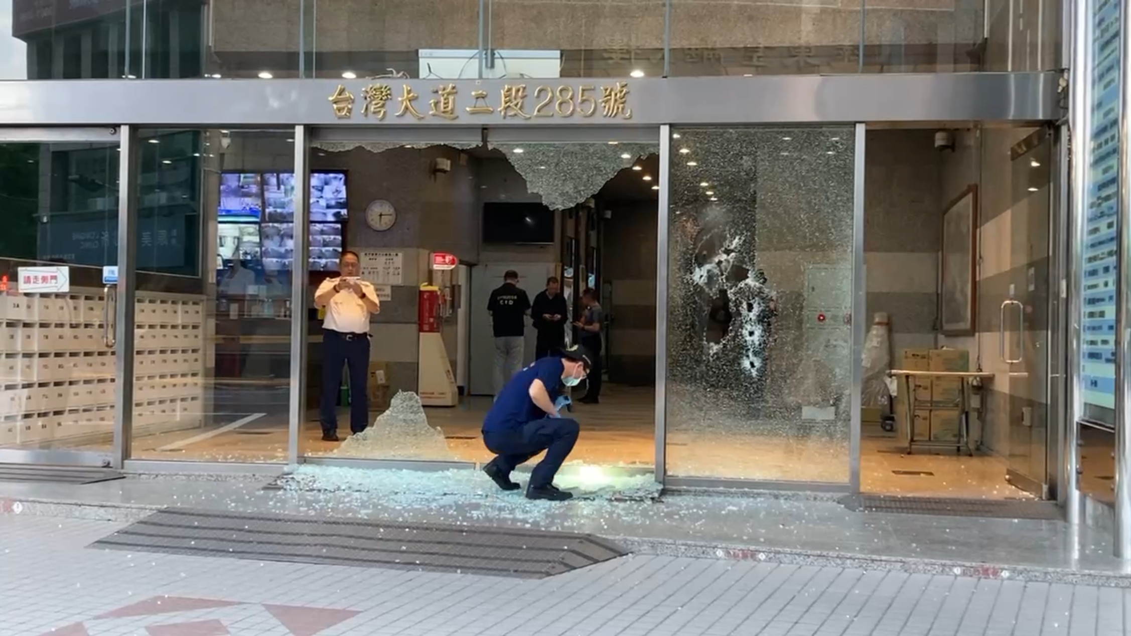 台灣大道商辦大門挨轟10幾槍,鑑識人員採證後,還有滿地玻璃等著清潔人員處理。
