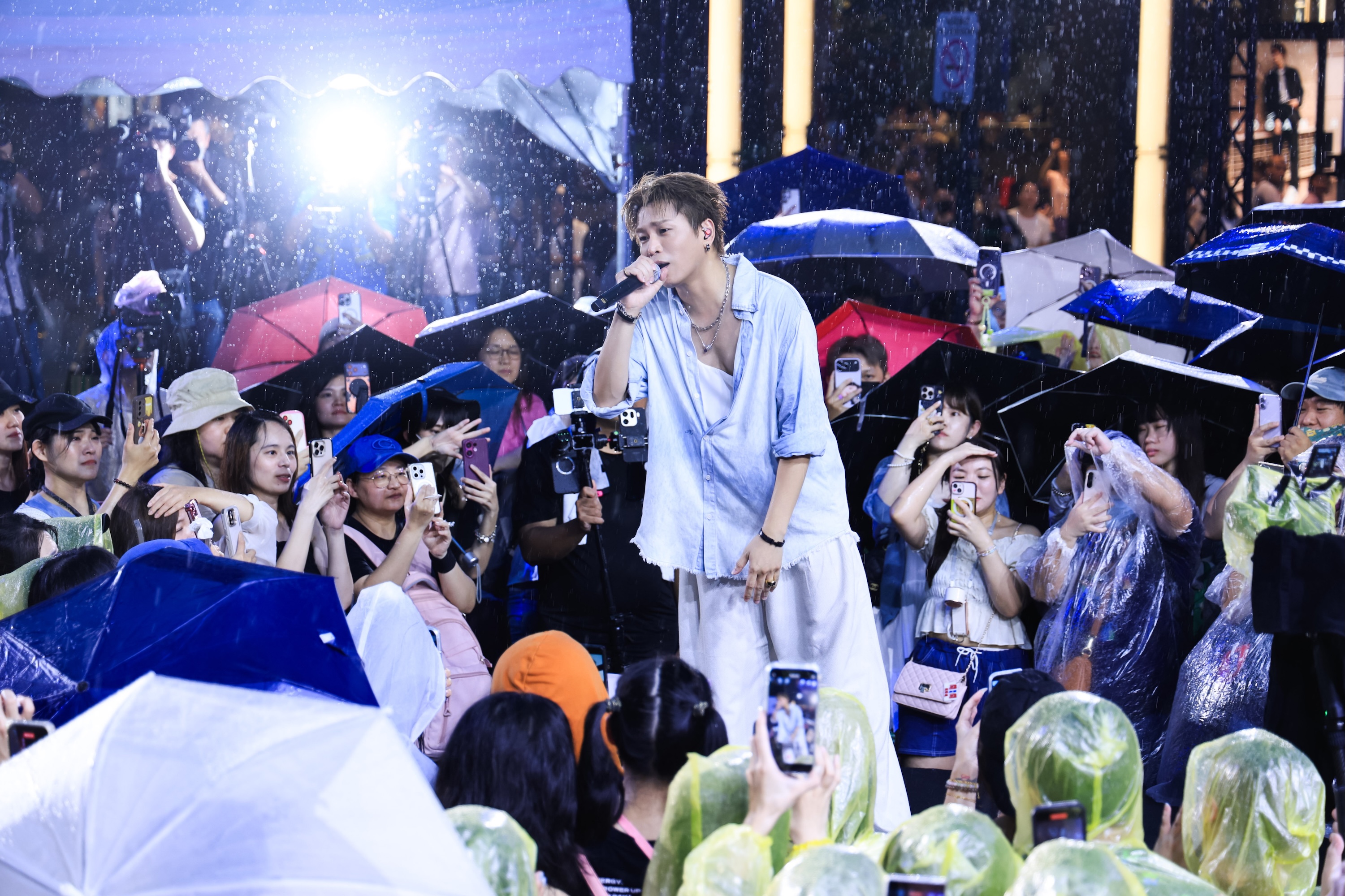 蕭景鴻簽唱會遇上大雨,放下雨傘走進歌迷中,一邊演唱一邊與歌迷握手互動。(相信音樂提供)