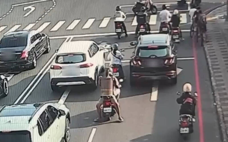 台南2名男子騎機車雙載,後座乘客竟反向坐抱約1公尺高的金爐上路。(翻攝畫面)