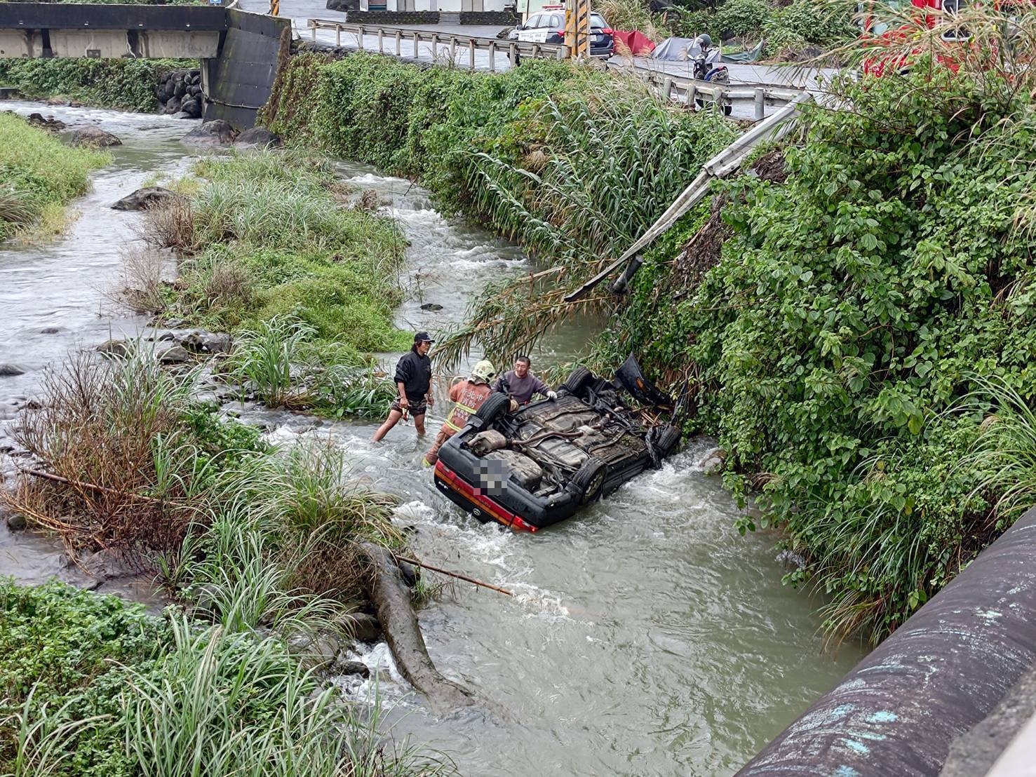 一輛自小客今日上午在貢寮區和美街墜落溪床,整輛車翻覆浸泡在急流中。(翻攝畫面)