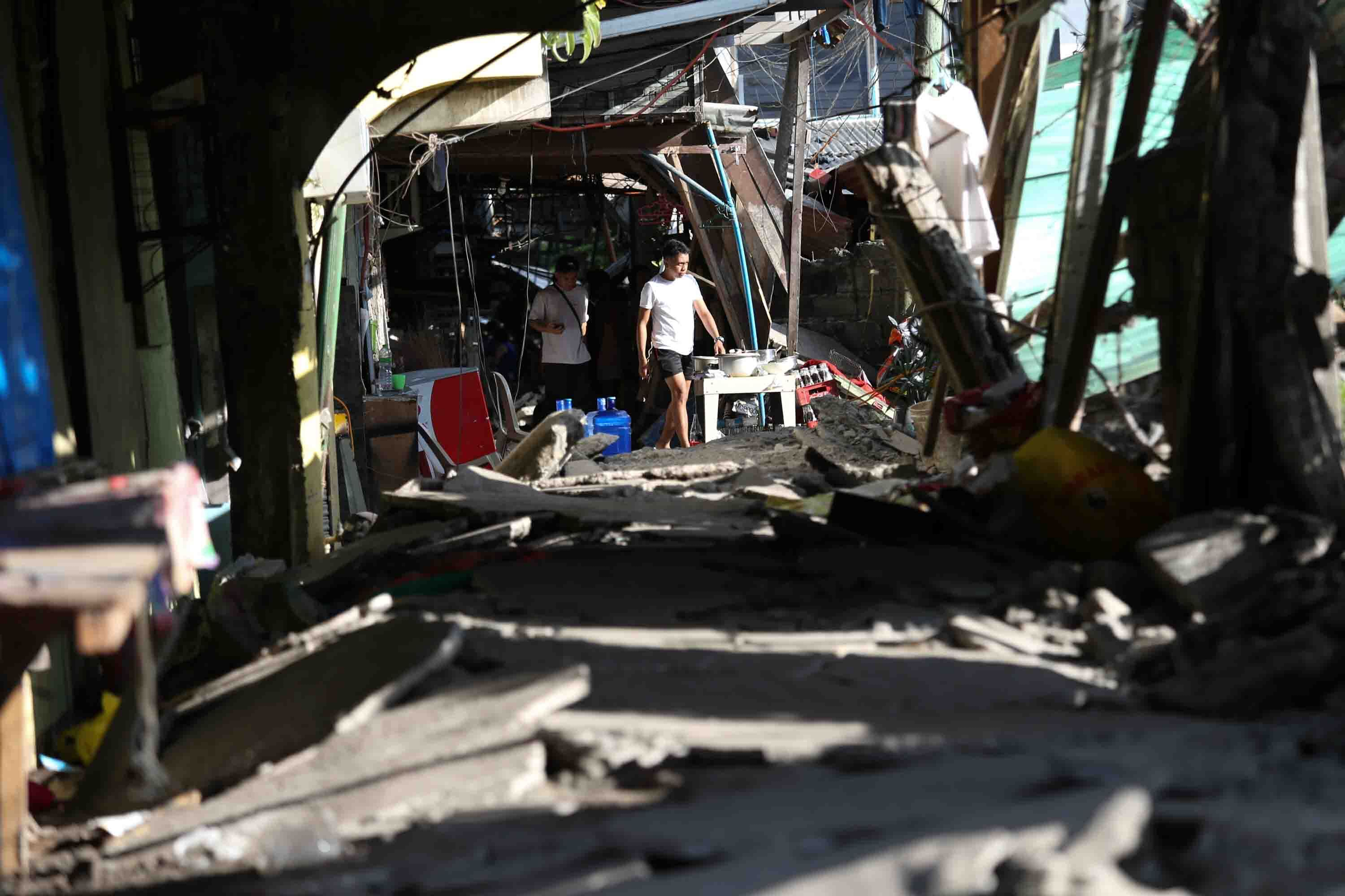 菲律賓聖托斯將軍市發生地震後,居民走在受損的人行道上。(AP)